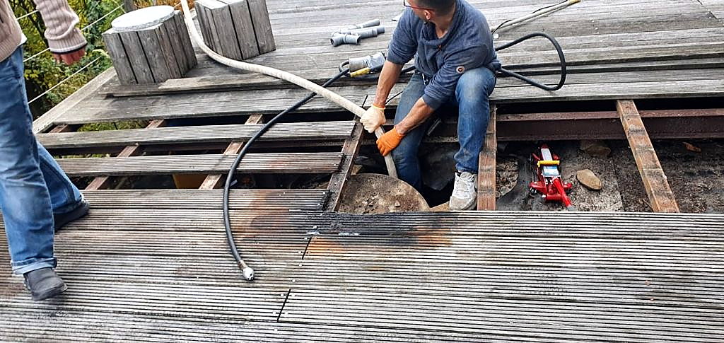 Thomas Kößler bei der Rohrreinigung in Fulda an Leitungen unter einer Holzterrasse.