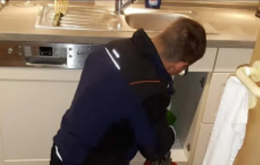 Mitarbeiter bei der Abflussreinigung unter einer Küchenspüle