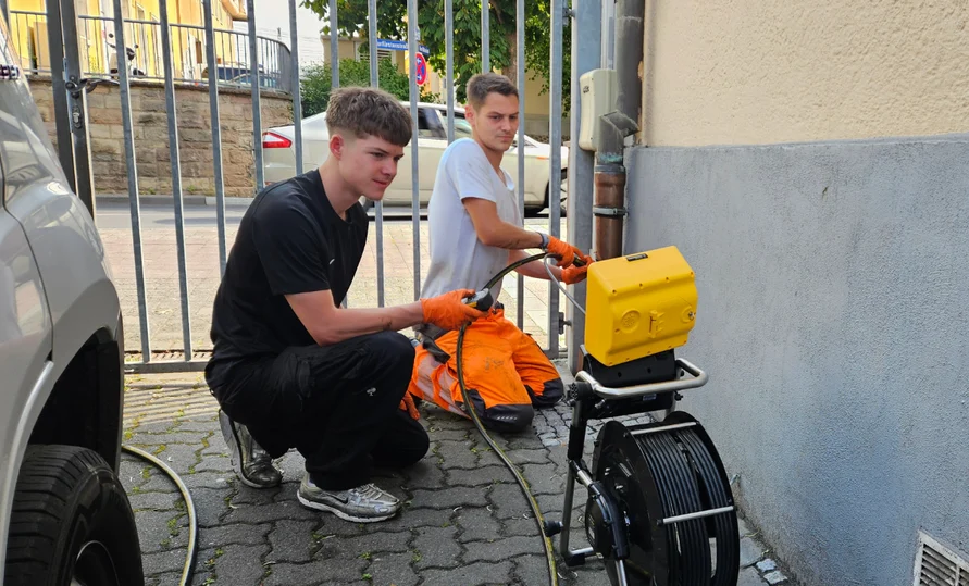 Mitarbeiter bei der Dachrinnenreinigung an einem Gebäude