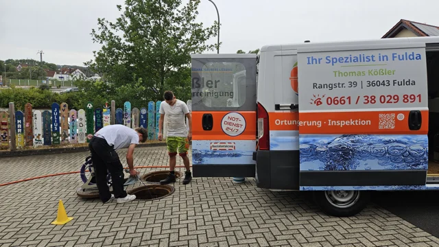TK-Rohrreinigung Fulda bei der Arbeit an einem Schacht vor dem Firmenfahrzeug